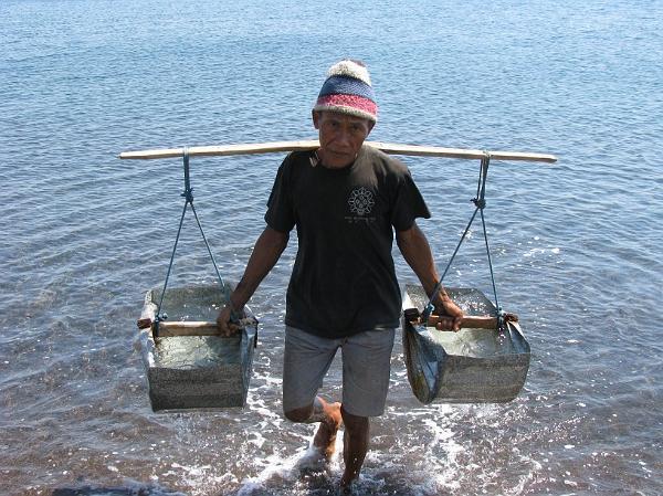 local man carrying sea water to make salt in Amed, Bali